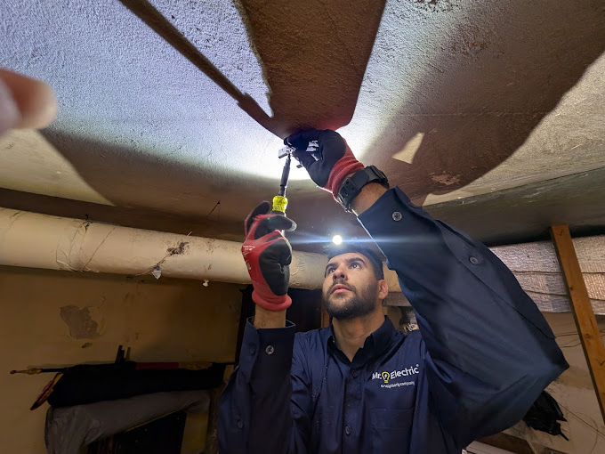 Mr. Electric technician repairing overhead lighting with a headlamp